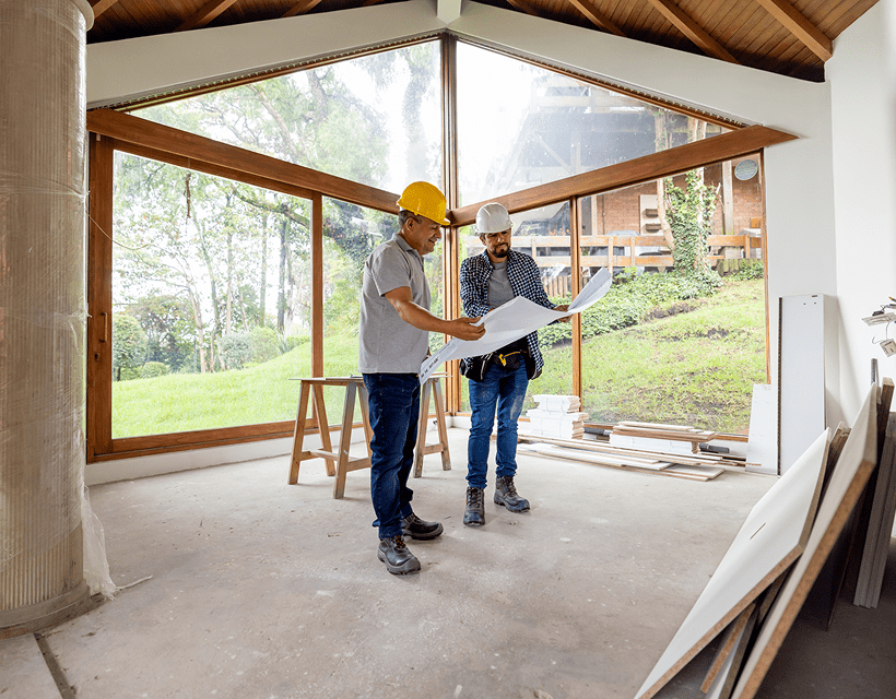 Construction workers reviewing building plans inside house.